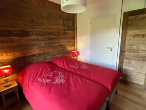 - une chambre avec un lit rouge et un mur en bois dans l'établissement Appartement Samoëns, 3 pièces, 4 personnes - FR-1-624-97, à Samoëns