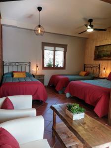 1 dormitorio con 2 camas, sofá y mesa en Hotel Rural La Covacha, en Losar de la Vera