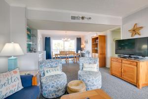 a living room with two chairs and a flat screen tv at Sunny Condo - Private Ocean Isle Beach Access! in Ocean Isle Beach