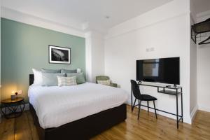 a bedroom with a bed and a desk and a tv at CitySpace Kings Cross in London