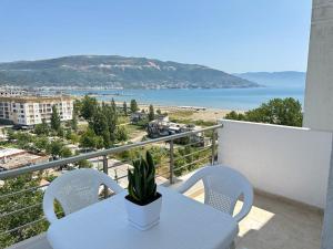 einen Tisch und Stühle auf einem Balkon mit Blick auf den Strand in der Unterkunft TreA Accomodations - Despacito Deluxe Sea View in Vlorë