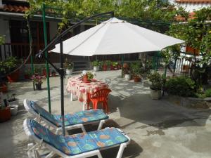 un tavolo con ombrellone bianco e due sedie e un tavolo con un tavolo di Pansion Giorgos & Rania a Città di Skiathos