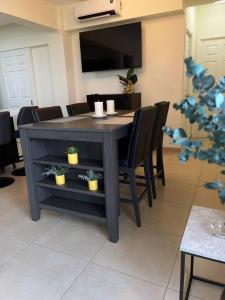Una mesa de comedor con sillas negras y un televisor. en Encanto Urbano, en San Salvador