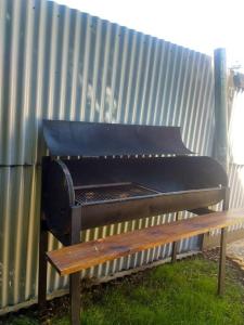 a grill sitting next to a bench next to a fence at Entre maitenes Bariloche in San Carlos de Bariloche