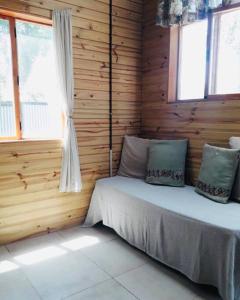 a bedroom with a bed with wooden walls and windows at Entre maitenes Bariloche in San Carlos de Bariloche