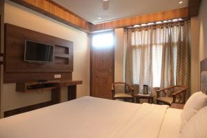 Habitación de hotel con cama y TV en Hotel Apple Blossom B$B en Manāli