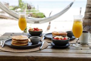 a table with pancakes and fruit and two glasses of orange juice at Sal Si Puedes in Tintipan Island