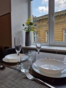 a table with plates and glasses and a vase with flowers at SOPRANO APARTMENT KRAKIVSKA 34 in Lviv