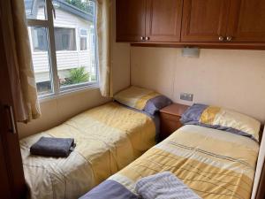 three beds in a small room with a window at Heacham Golden Sunset Caravan Pets go Free in Hunstanton