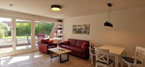 ein Wohnzimmer mit einem roten Sofa und einem Tisch in der Unterkunft Achtern Diek in Horumersiel