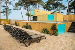 - une rangée de chaises longues sur la plage dans l'établissement Ohai Nazaré Outdoor Resort, à Nazaré