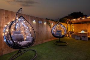 duas cadeiras penduradas com luzes numa cerca em Exquisite Cardiff Apartments- with Garden Lounge & Games Room em Cardiff
