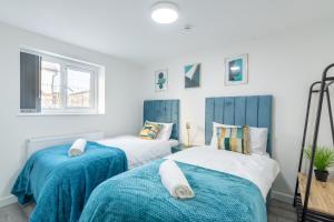 two beds in a room with blue and white at Exquisite Cardiff Apartments- with Garden Lounge & Games Room in Cardiff