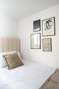 a bedroom with a white bed with pictures on the wall at Exquisite Cardiff Apartments- with Garden Lounge & Games Room in Cardiff