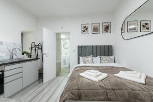 a white bedroom with a large bed and a sink at Exquisite Cardiff Apartments- with Garden Lounge & Games Room in Cardiff