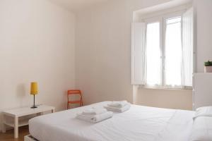 ein weißes Schlafzimmer mit einem weißen Bett und einem Stuhl in der Unterkunft YouHosty - Correggio 55 B in Mailand