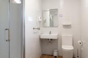 a white bathroom with a toilet and a sink at Hotel Playa Las Sinas in Villanueva de Arosa +25 photos