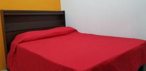 a bed with a red blanket on top of it at REGIOTITLAN-PARQUE FUNDIDORA in Monterrey