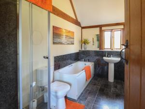 a bathroom with a tub and a toilet and a sink at Ysgubor Fachwen in Newtown +16 photos