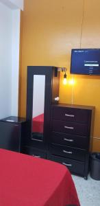 a bedroom with a dresser with a mirror and a tv at REGIOTITLAN-PARQUE FUNDIDORA in Monterrey