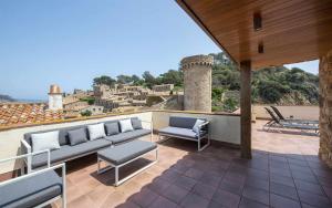a patio with couches and chairs on a roof at Luxury Rocamar Primera línea de marTerraza in Tossa de Mar