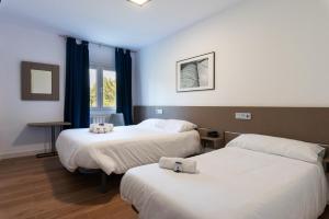 a hotel room with two beds and a window at Hotel Playa Las Sinas in Villanueva de Arosa