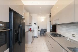 a kitchen with white cabinets and a black refrigerator at Easylife - Elegante attico 2 min da Parco Sempione in Milan