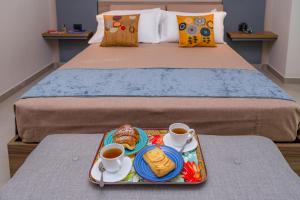 una bandeja de comida en una cama con dos tazas de café en Macramè Fazello Rooms, en Sciacca