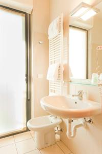 a bathroom with a sink and a toilet and a mirror at Agorà Hotel in Calamandrana