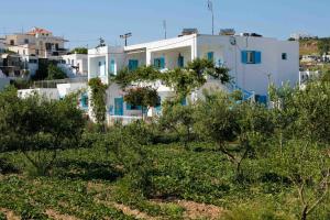 une maison blanche avec des fenêtres bleues dans un village dans l'établissement Mira Mare Studios, à Lipsi