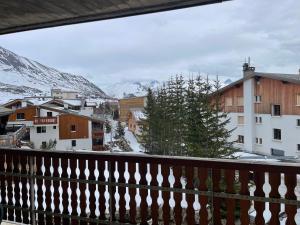 een balkon met uitzicht op een stad met besneeuwde bergen bij L'ALPE D'HUEZ Appartement 4 couchages idéalement situé in Huez +8 foto's