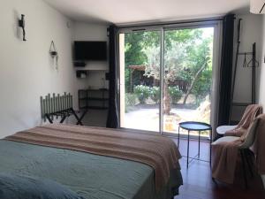 a bedroom with a bed and a sliding glass door at La Maison 1440 in L'Isle-sur-la-Sorgue