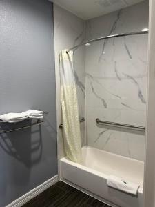 y baño con ducha, bañera y lavamanos. en Atlantis Inn Suites, en Houston