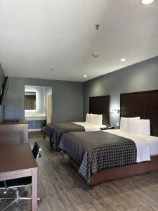 Habitación de hotel con 2 camas y escritorio en Atlantis Inn Suites en Houston