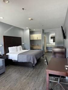 Habitación de hotel con cama grande y escritorio. en Atlantis Inn Suites en Houston