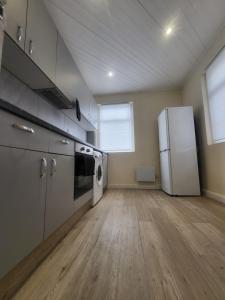 a large kitchen with a refrigerator and a wooden floor at Beautiful 2-bed flat in the heart of Hendon in The Hyde