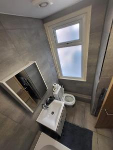 La salle de bains est pourvue de toilettes, d'un lavabo et d'une fenêtre. dans l'établissement Beautiful 2-bed flat in the heart of Hendon, à The Hyde