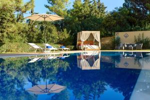 a pool with two chairs and an umbrella next to it at Kallithea Breeze Luxury Villa in Koskinou