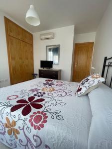 een slaapkamer met een bed met een bloemenbed bij Piso con parking y piscina en Torrox costa in Torrox Costa