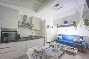 a living room with a blue couch and a kitchen at Sun&Garden Flat in Cagliari