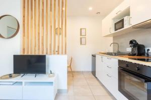 a kitchen with white cabinets and a large tv at T2 plain-pied à 3 minutes du centre in Castres