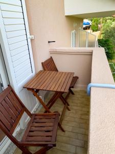 einen Holztisch und zwei Stühle auf dem Balkon in der Unterkunft Haus Lupić in Rab
