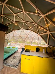 a yellow kitchen in a room with a glass ceiling at Čiki Puki Glamping in Palanga