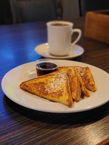 ein weißer Teller mit französischem Toast und einer Tasse Kaffee in der Unterkunft Stonebridge Hotel in Fort McMurray