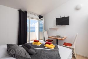 a bedroom with a bed and a desk and a television at Beach Apartments Borovina in Stanići
