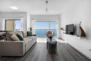 - un salon blanc avec un canapé et une télévision dans l'établissement Janelas de Zimbra - Lovely Apartment with Pool and Sea View, à Sesimbra