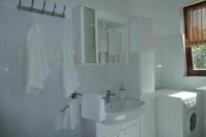 a white bathroom with a sink and a washing machine at House Meli in Rakalj