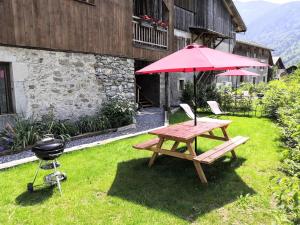 a picnic table with a grill and a red umbrella at Chez Lucienne in Samoëns