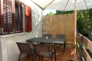 a table and chairs on a balcony with an umbrella at House Meli in Rakalj +45 photos