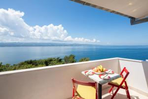 einen Tisch und Stühle auf einem Balkon mit Blick auf das Wasser in der Unterkunft Beach Apartments Borovina in Stanići